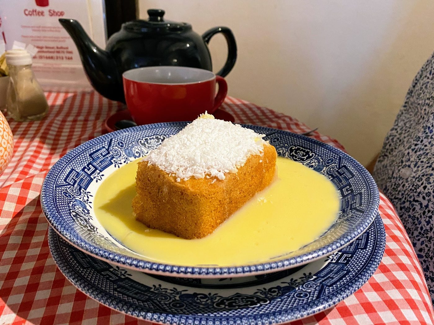 A sponge pudding with custard and a teapot