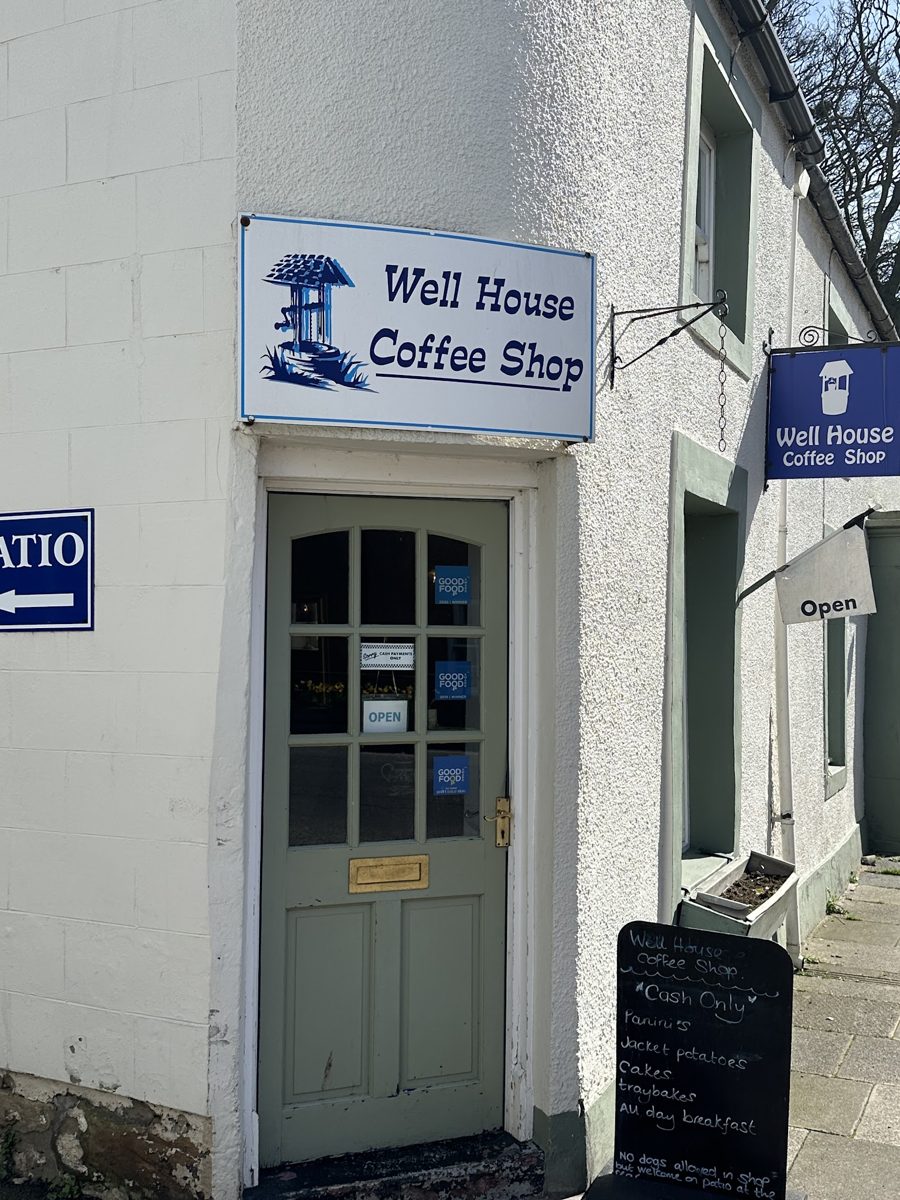 The white corner building with the Well House Coffee Shop sign over the door